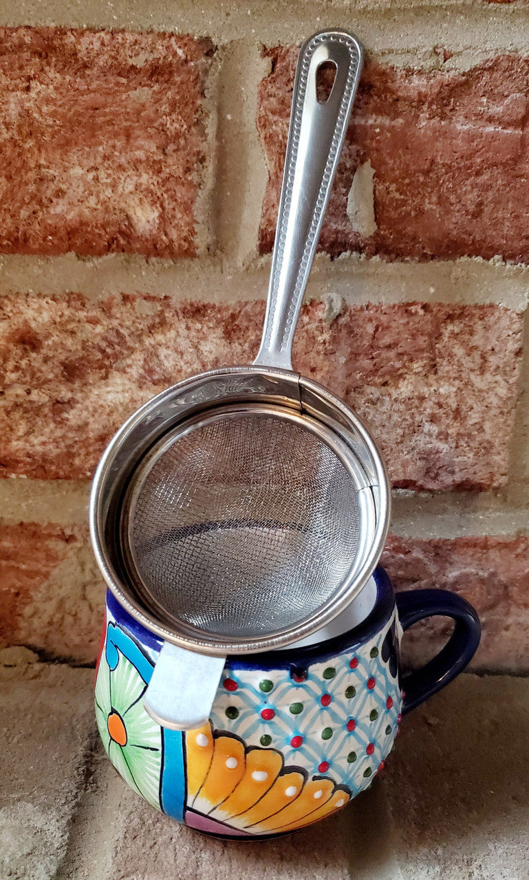 Stainless steel chai strainer resting on a colorful mug for loose leaf chai brewing